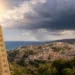 Termometro in primo piano mostra temperature oltre 35°C con panorama di Ragusa Ibla sullo sfondo e nuvole temporalesche