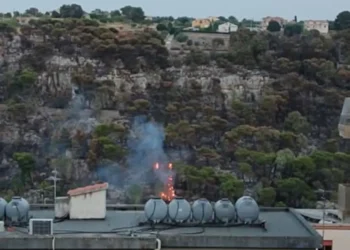 Fiamme e fumo sul versante del Parco di Monserrato a Modica, con la collina interessata dall'incendio sullo sfondo delle abitazioni della Vetta.