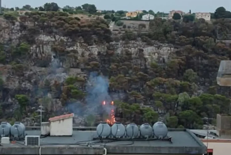 Fiamme e fumo sul versante del Parco di Monserrato a Modica, con la collina interessata dall'incendio sullo sfondo delle abitazioni della Vetta.