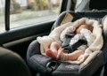 Neonato in ovetto allacciato nel sedile posteriore di un'auto. Immagine di repertorio