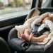 Neonato in ovetto allacciato nel sedile posteriore di un'auto. Immagine di repertorio