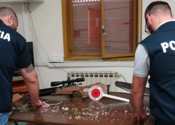 Agenti della Polizia di Stato mostrano su un tavolo i gioielli e gli oggetti sequestrati a Niscemi durante un'operazione che ha portato alla denuncia di tre persone per ricettazione.