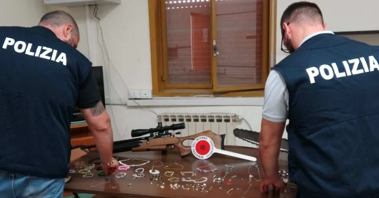 Agenti della Polizia di Stato mostrano su un tavolo i gioielli e gli oggetti sequestrati a Niscemi durante un'operazione che ha portato alla denuncia di tre persone per ricettazione.