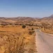 Paesaggio siciliano assolato con terreno arido e vegetazione secca durante un’ondata di calore.