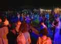 Folla che balla all'aperto di notte durante il Palio delle Contrade di Ragusa a Puntarazzi, con luci colorate e tendoni food.