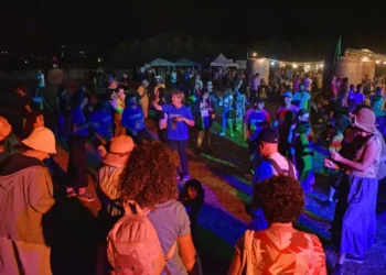 Folla che balla all'aperto di notte durante il Palio delle Contrade di Ragusa a Puntarazzi, con luci colorate e tendoni food.