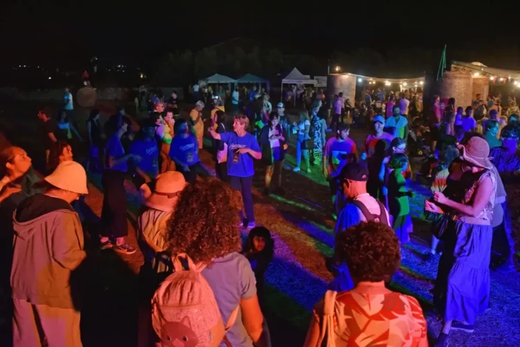 Folla che balla all'aperto di notte durante il Palio delle Contrade di Ragusa a Puntarazzi, con luci colorate e tendoni food.