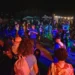 Folla che balla all'aperto di notte durante il Palio delle Contrade di Ragusa a Puntarazzi, con luci colorate e tendoni food.