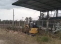 Mini escavatore CAT al lavoro lungo il perimetro del campo sportivo di Pedalino, accanto alla tribuna metallica