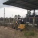 Mini escavatore CAT al lavoro lungo il perimetro del campo sportivo di Pedalino, accanto alla tribuna metallica