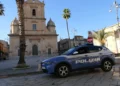 Auto della Polizia di Stato parcheggiata in piazza a Vittoria davanti a una chiesa del centro storico durante un servizio di polizia