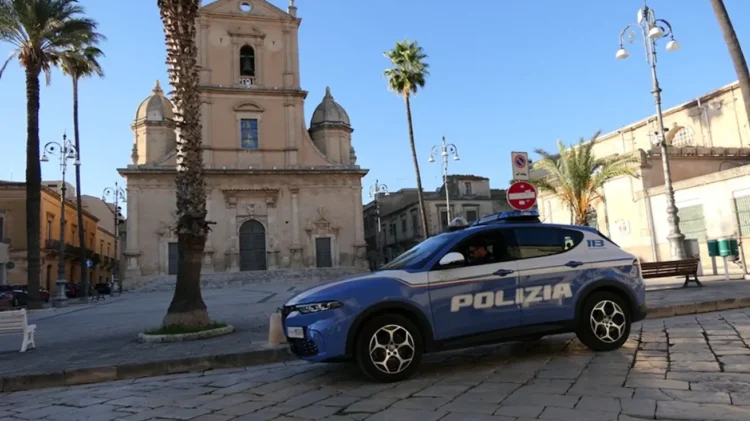 Auto della Polizia di Stato parcheggiata in piazza a Vittoria davanti a una chiesa del centro storico durante un servizio di polizia