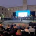Il palco del Premio Ragusani nel Mondo allestito in Piazza Libertà a Ragusa durante la cerimonia, con il pubblico presente e l'orchestra sullo sfondo.