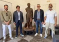 La statua restaurata della Tomba dei Picialuori esposta al Museo della Città di Ragusa, affiancata da quattro persone durante la presentazione del recupero.
