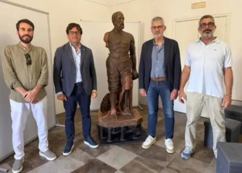 La statua restaurata della Tomba dei Picialuori esposta al Museo della Città di Ragusa, affiancata da quattro persone durante la presentazione del recupero.
