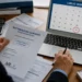 Persona alla scrivania con un documento sulla rottamazione quinquies e un computer che mostra il calendario di luglio 2026 con la data del 31 luglio evidenziata