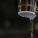 Primo piano di un rubinetto da cui esce un sottile filo d'acqua, immagine simbolo dei disagi legati alla carenza idrica e ai blackout