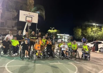 Atleti della Crazy Wheels Ragusa, ospiti e Vigili del Fuoco posano insieme sul campo al termine del torneo Ruote Pazze Ragusa di basket in carrozzina a Marina di Ragusa