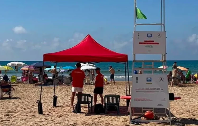Due assistenti bagnanti in maglietta rossa sorvegliano la spiaggia di Marina di Ragusa accanto alla torretta di avvistamento