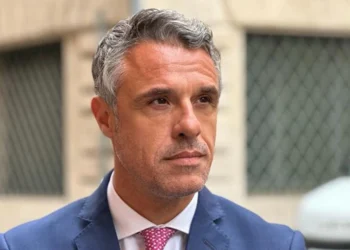 Il senatore Salvo Sallemi in giacca blu e cravatta rosa durante un'intervista, interviene sul dibattito riguardante il mercato ortofrutticolo di Vittoria e le infiltrazioni mafiose