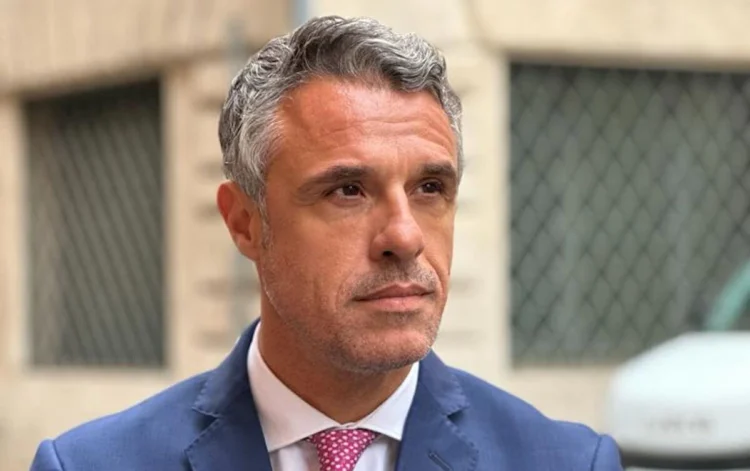 Il senatore Salvo Sallemi in giacca blu e cravatta rosa durante un'intervista, interviene sul dibattito riguardante il mercato ortofrutticolo di Vittoria e le infiltrazioni mafiose
