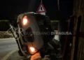 Auto ribaltata su un fianco dopo un incidente sulla strada provinciale Scicli-Sampieri, con il muro di recinzione distrutto dall'impatto.
