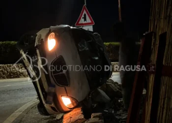 Auto ribaltata su un fianco dopo un incidente sulla strada provinciale Scicli-Sampieri, con il muro di recinzione distrutto dall'impatto.