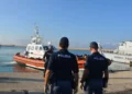 Motovedetta della Guardia Costiera con migranti in arrivo al porto di Pozzallo, mentre agenti della Polizia assistono alle operazioni di sbarco