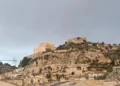 Veduta panoramica del colle di San Matteo a Scicli con l'antica chiesa sulla sommità e il centro storico ai piedi della collina sotto un cielo nuvoloso
