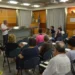 Riunione di medici di famiglia in una sala istituzionale con bandiere italiana ed europea, due relatori in piedi davanti ai presenti