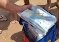 Mazzette di banconote da 20 euro in sacchetti di plastica trasparenti estratti da una borsa frigo colorata su una spiaggia