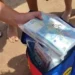 Mazzette di banconote da 20 euro in sacchetti di plastica trasparenti estratti da una borsa frigo colorata su una spiaggia