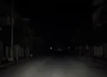 Strada urbana di Pozzallo completamente al buio durante un blackout elettrico, con illuminazione pubblica assente e carreggiata deserta nelle ore notturne.