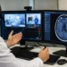 Un neurologo effettua una consulenza in telemedicina davanti a due monitor con immagini diagnostiche cerebrali e un collegamento video con un reparto ospedaliero