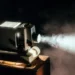 Proiettore cinematografico d'epoca acceso che proietta un fascio di luce in una stanza buia, con il fumo che rende visibile il raggio luminoso