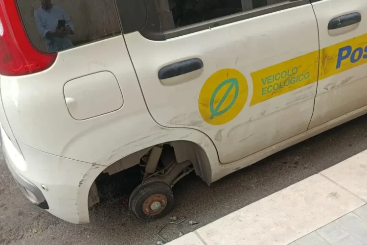 Auto di servizio delle Poste senza una ruota, parcheggiata davanti all'ufficio postale di Vittoria dopo il furto