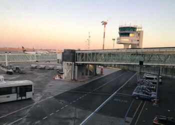 Piazzale dell'aeroporto di Catania Fontanarossa all'alba: torre di controllo, finger e un aereo Ryanair in pista