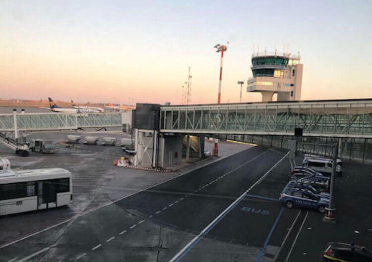 Piazzale dell'aeroporto di Catania Fontanarossa all'alba: torre di controllo, finger e un aereo Ryanair in pista
