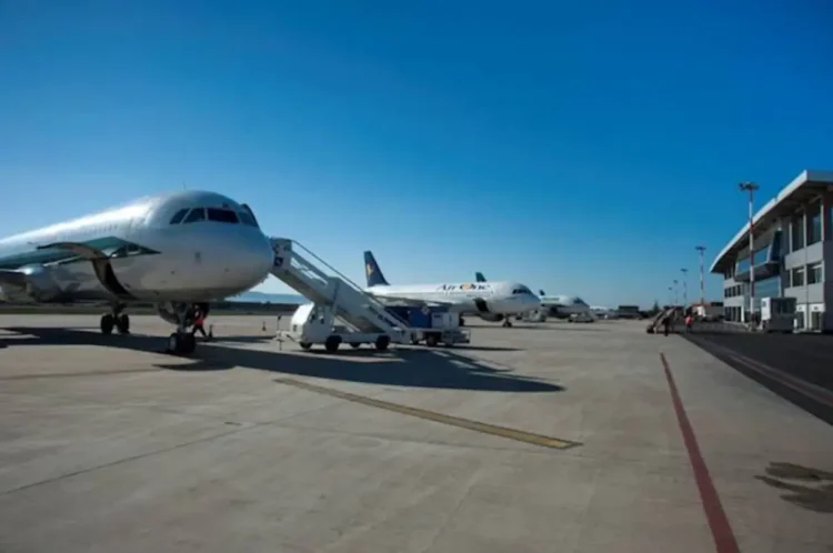 Pista dell'aeroporto di Comiso con due aerei di linea in sosta davanti al terminal, cielo sereno.