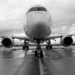 Vista frontale di un aereo di linea fermo in pista, carrelli a terra, cielo nuvoloso