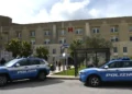 Due volanti della Polizia di Stato parcheggiate davanti all'ingresso di un ospedale, con la lettera H rossa in facciata.