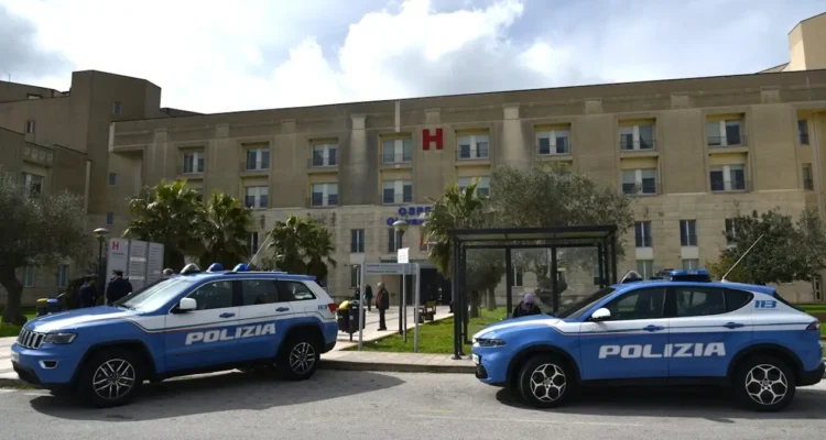 Due volanti della Polizia di Stato parcheggiate davanti all'ingresso di un ospedale, con la lettera H rossa in facciata.