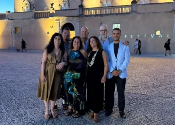 Sette membri del direttivo AIDC Ragusa in posa davanti a un edificio storico illuminato durante un evento serale
