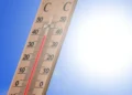 Termometro da esterno con la colonnina di mercurio sopra i 40 gradi, cielo azzurro e sole intenso sullo sfondo.