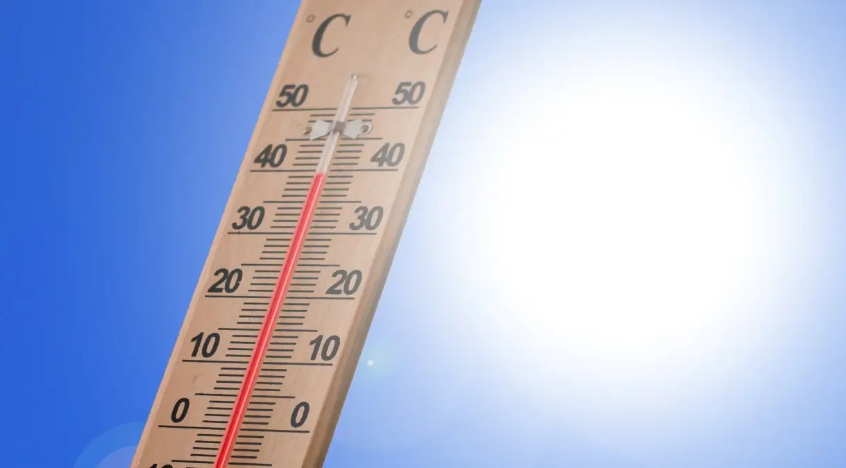 Termometro da esterno con la colonnina di mercurio sopra i 40 gradi, cielo azzurro e sole intenso sullo sfondo.
