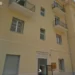 Facciata di un edificio popolare con balconi in muratura, persiane chiuse e bandiere esposte, a Pozzallo.