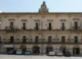 Facciata di Palazzo San Domenico a Modica, sede del Comune, con orologio e bandiere italiane ed europee