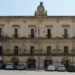 Facciata di Palazzo San Domenico a Modica, sede del Comune, con orologio e bandiere italiane ed europee
