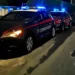 Due auto dei Carabinieri con lampeggianti blu accesi in una strada di notte, logo Carabinieri Ragusa in basso a destra.