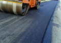 Rullo compressore stende asfalto fresco su una strada durante lavori di manutenzione stradale